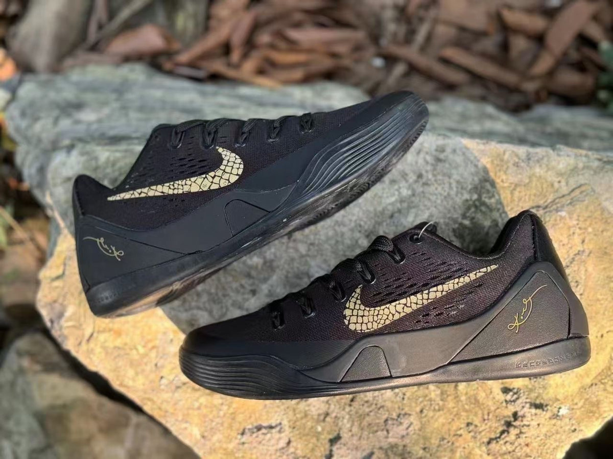 Pair of black Kobe 9 basketball shoes with gold-toned Swoosh graphics.
