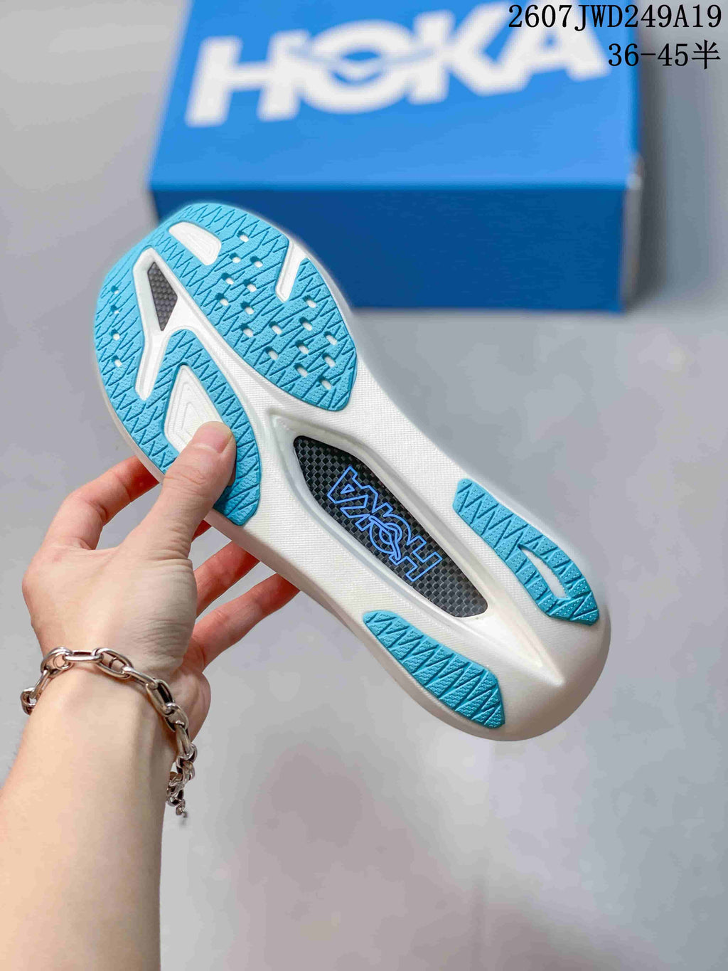 Close view of the sneaker outsole showing blue patterned rubber sections, white sole areas, and a central black insert.