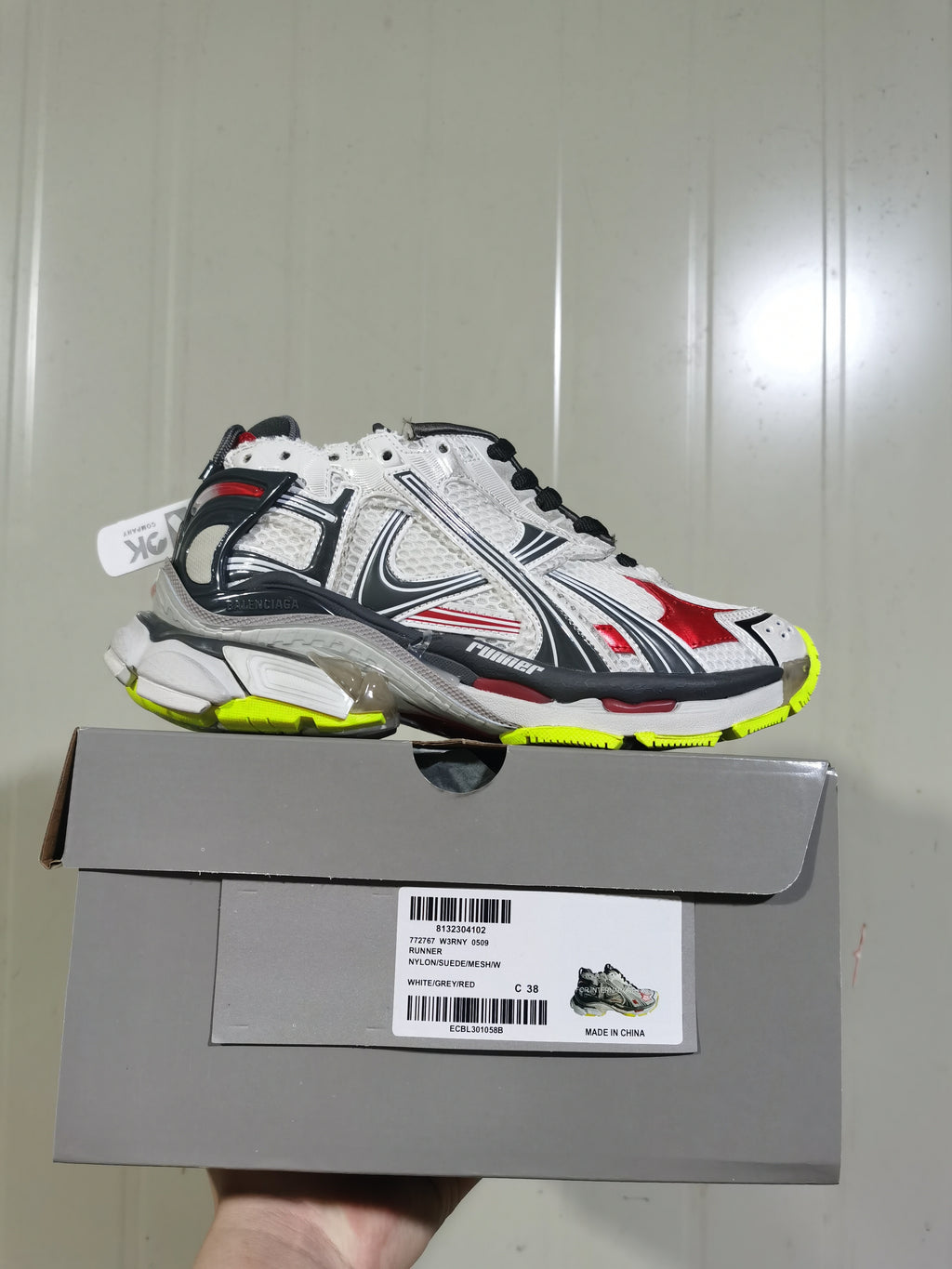 Balenciaga Runner sneaker in white, grey, black, red and fluorescent yellow shown on its box; the box label shows size C 38.