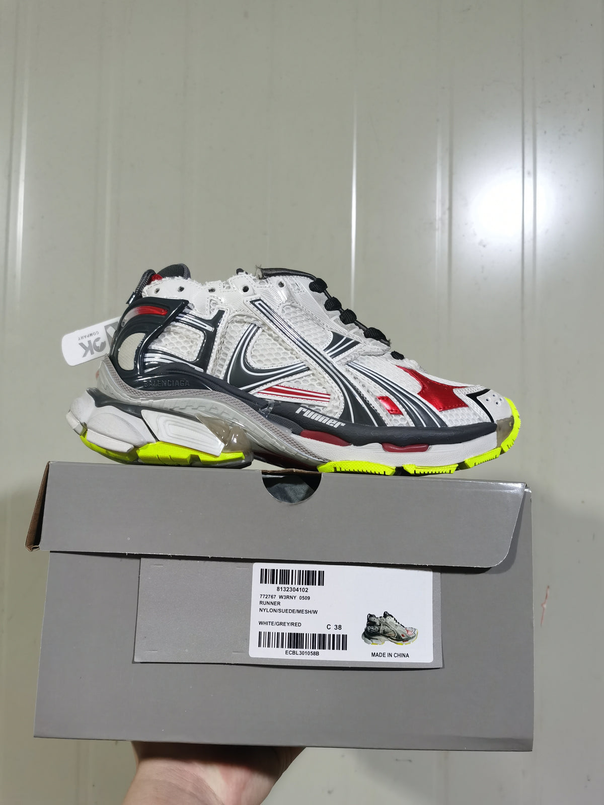 Balenciaga Runner sneaker in white, grey, black, red and fluorescent yellow shown on its box; the box label shows size C 38.