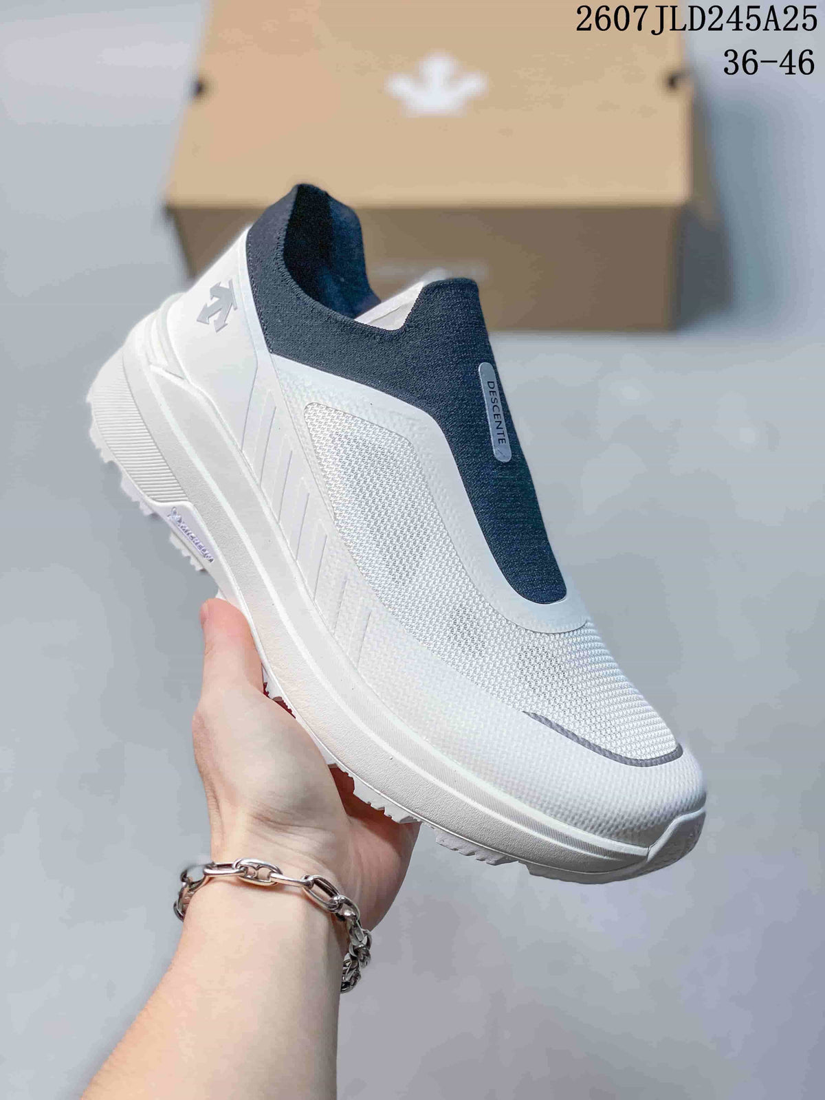 Angled side view of the white DESCENTE sneaker with navy collar and central panel, textured upper, and thick outsole.
