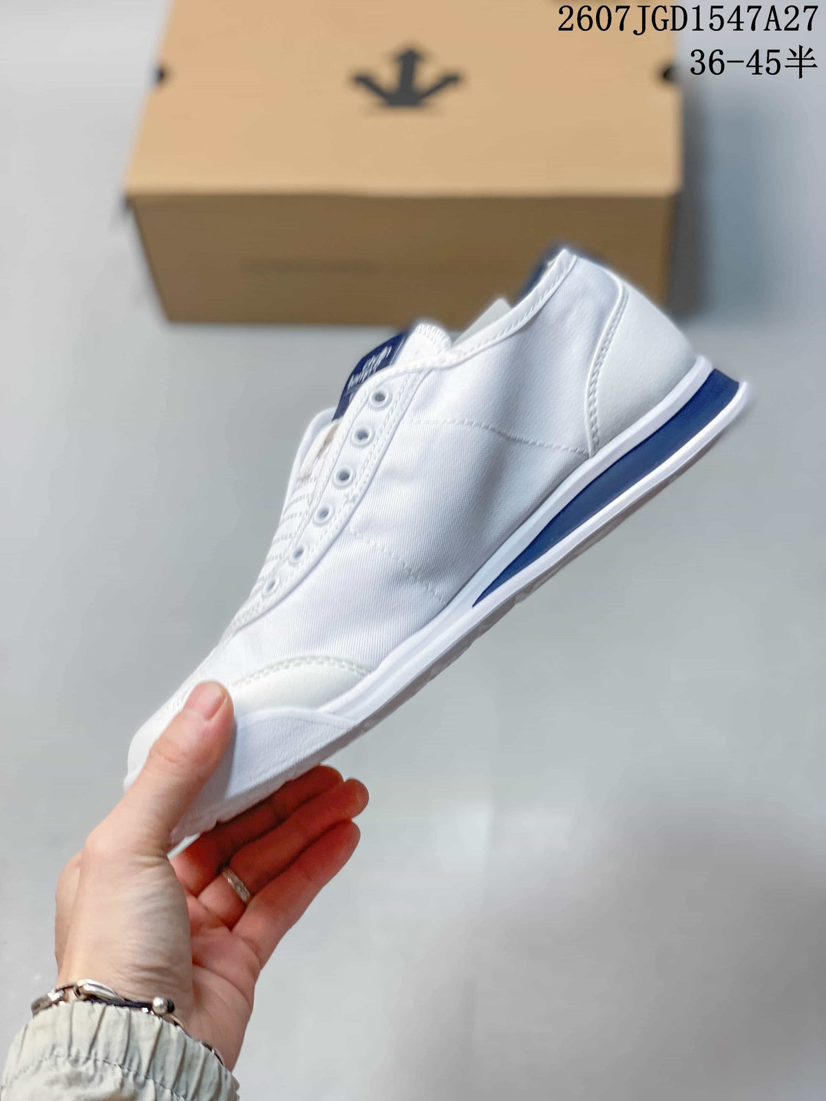 Side profile showing the white upper, stitched panels, blue midsole accent, and low-top shape.