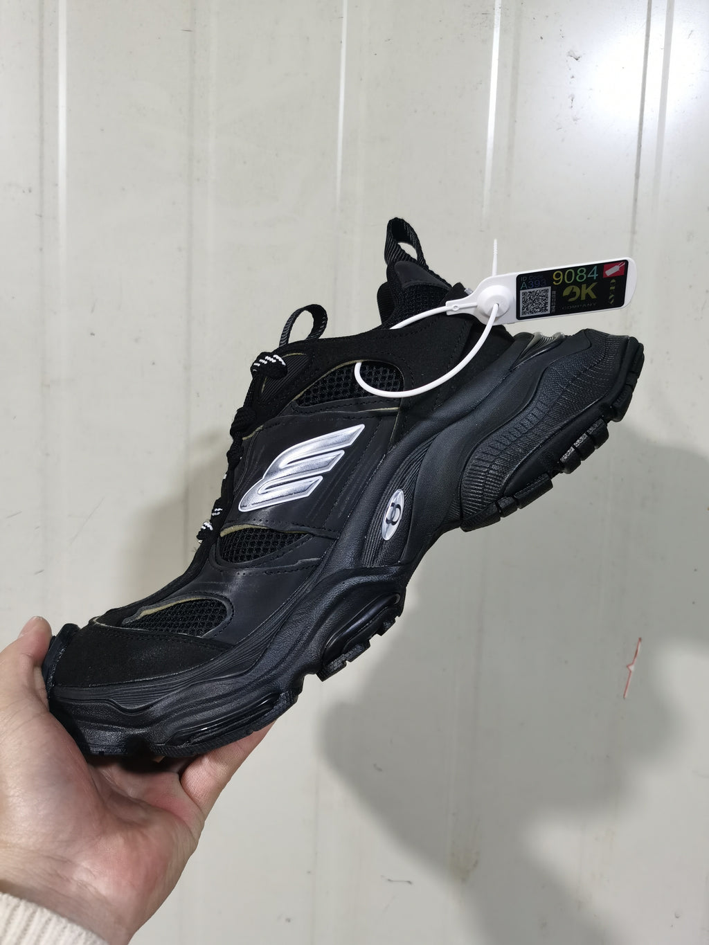 Rear and side angled view of the black and white sneaker showing the pull tabs, textured outsole, and metallic side detailing.