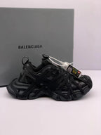 Pair of black Balenciaga 3XL-style sneakers shown from the side with layered laces and a chunky outsole.