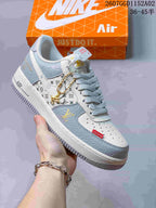 Side view of an off-white and pale grey patterned low-top sneaker with gold-tone details and a lace charm.