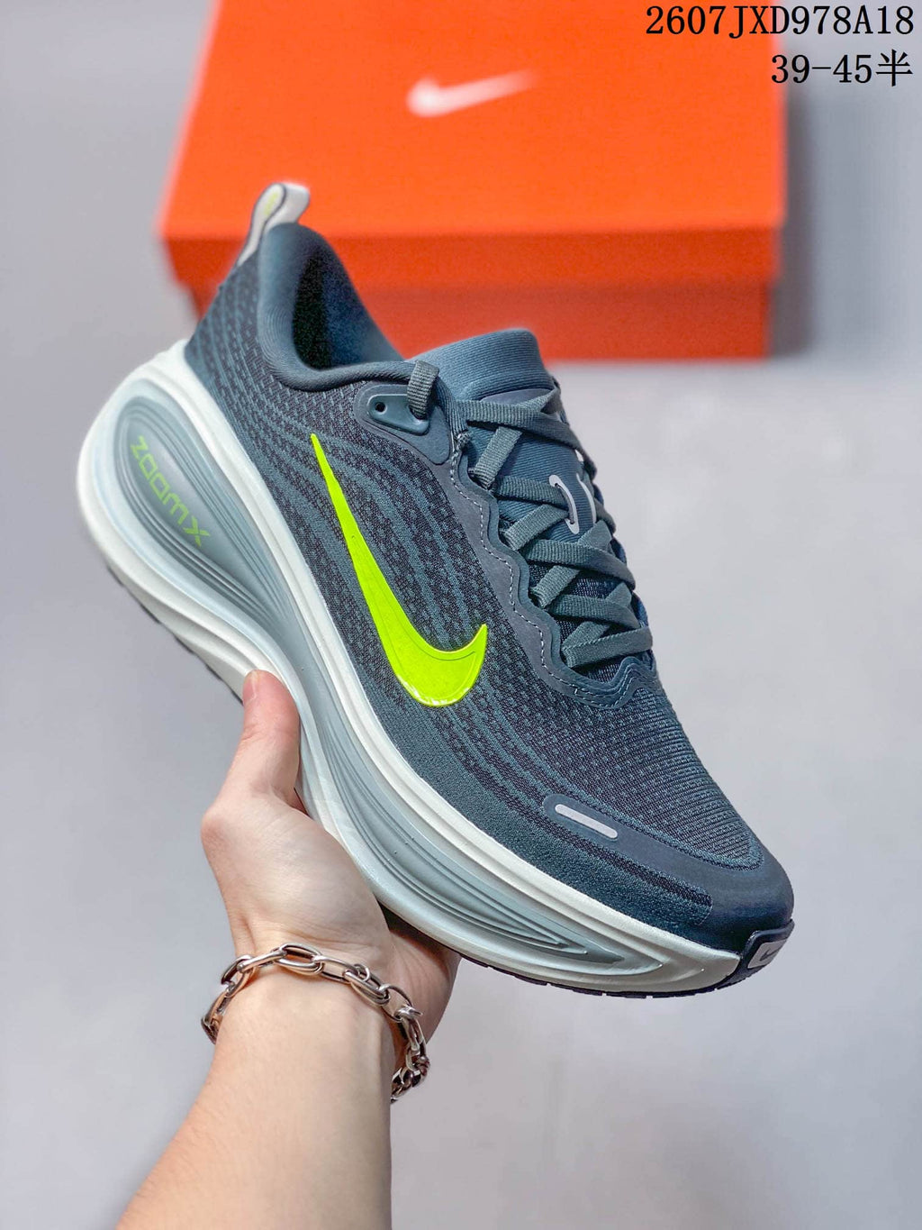 Dark blue-gray Nike Vomero Plus running shoe with a neon yellow swoosh and light-colored midsole.
