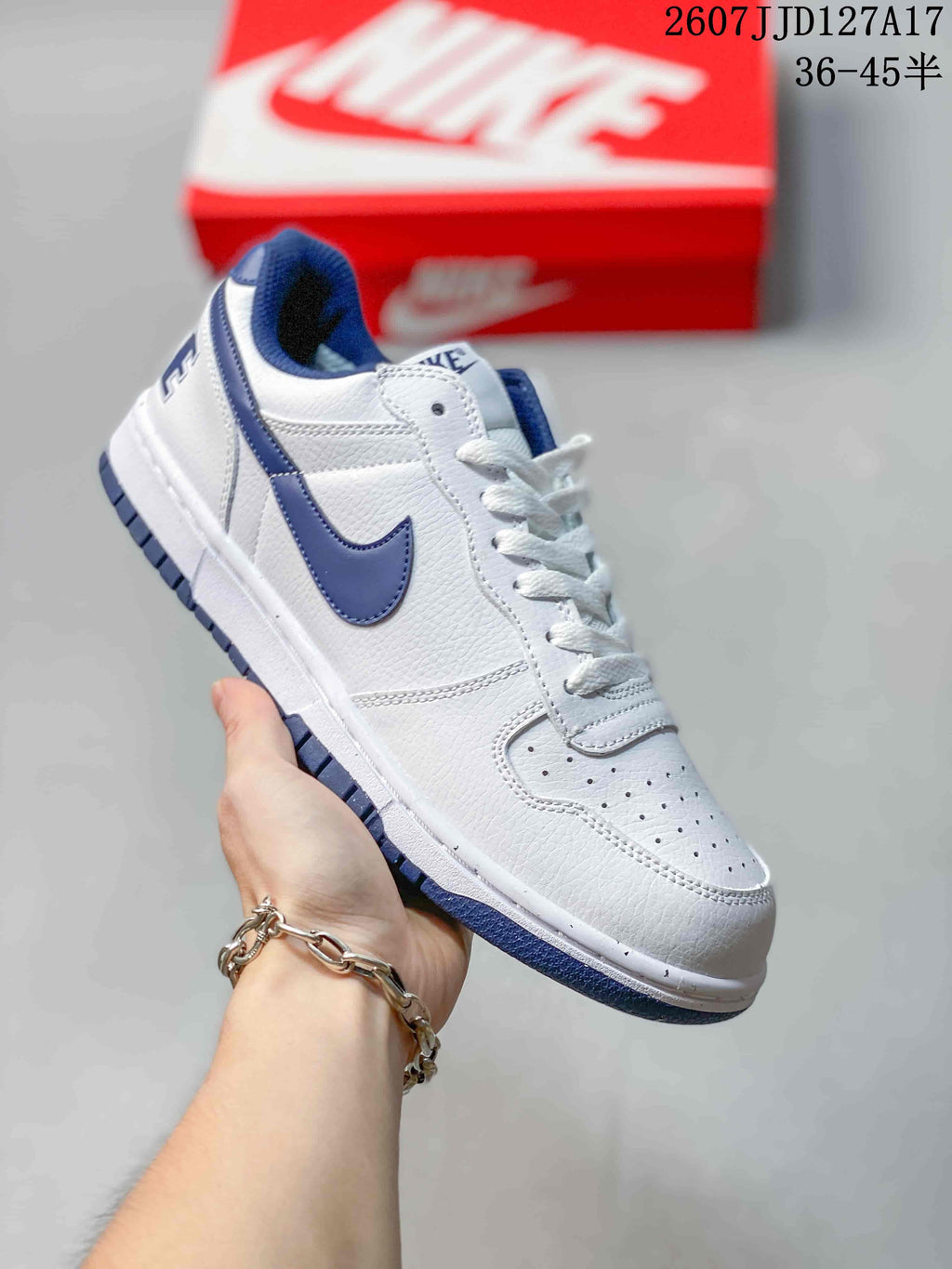 White Nike SB Dunk Low Pro sneaker with dark blue Swoosh, collar, tongue, and outsole accents.