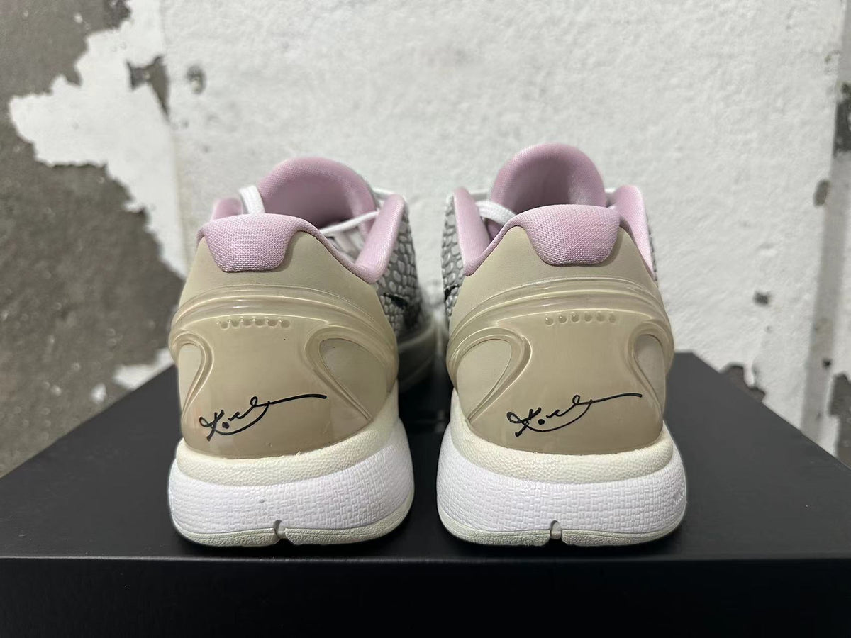 Rear view of white and grey Nike basketball shoes with pale pink collar lining and heel graphics.