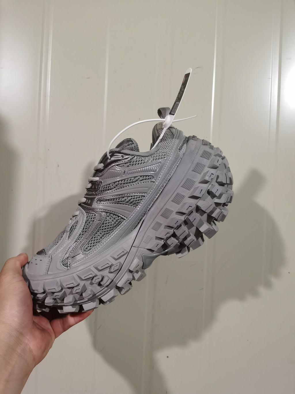 Side view of a grey Balenciaga Defender sneaker showing its layered upper and chunky lugged outsole.
