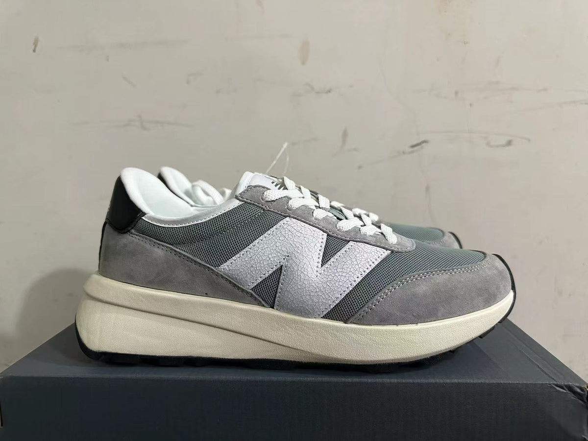 Side view of a gray New Balance U370 sneaker with a large light-colored logo.