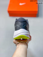 Rear view of the gray sneaker showing the padded collar, white midsole, and neon green outsole edge.