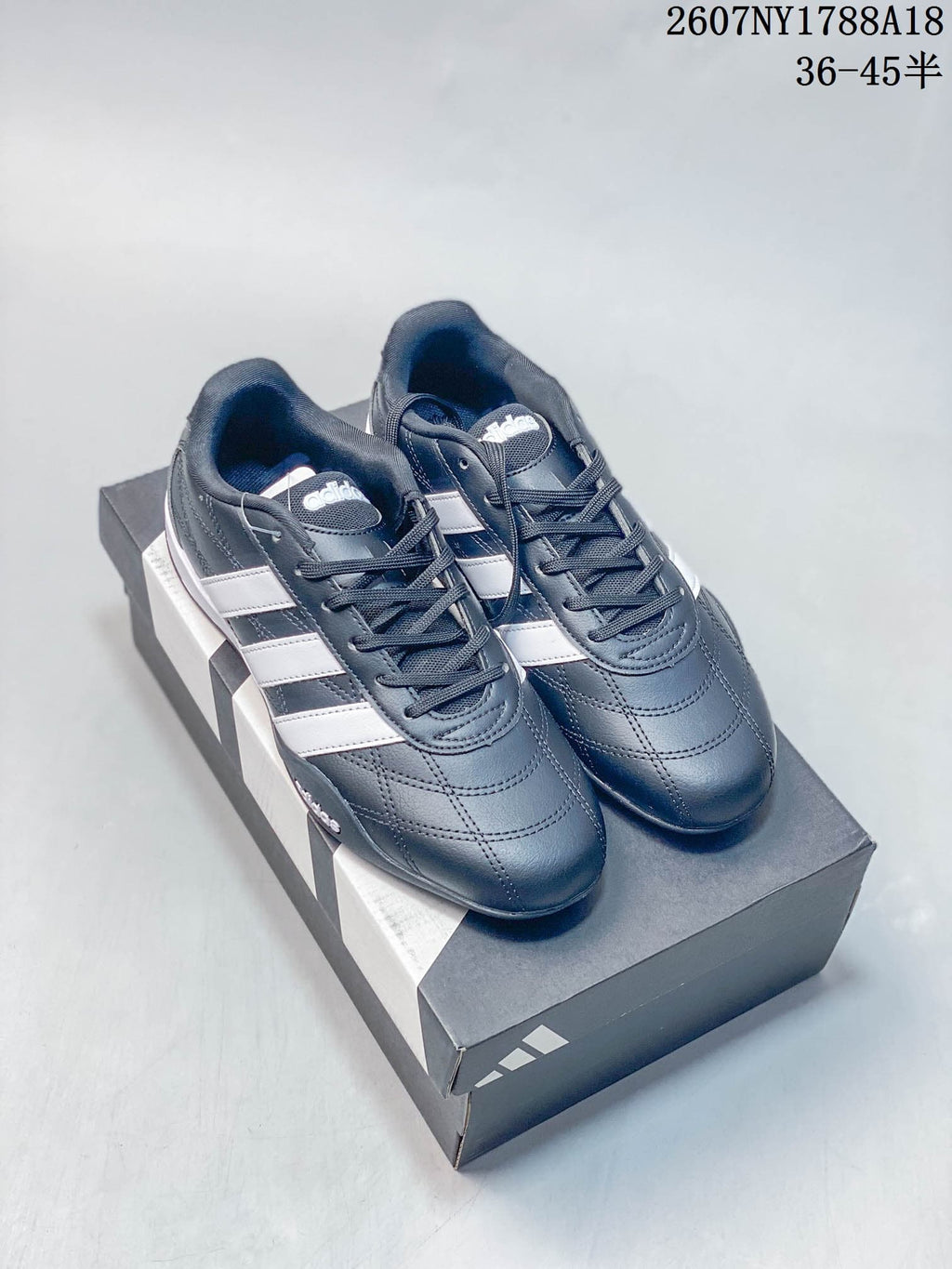 Pair of navy adidas Adipista sneakers with white stripes displayed on a shoebox.