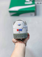 Rear view of the white sneaker showing a BMW roundel detail, colored stripe accent, and PUMA branding on the heel.