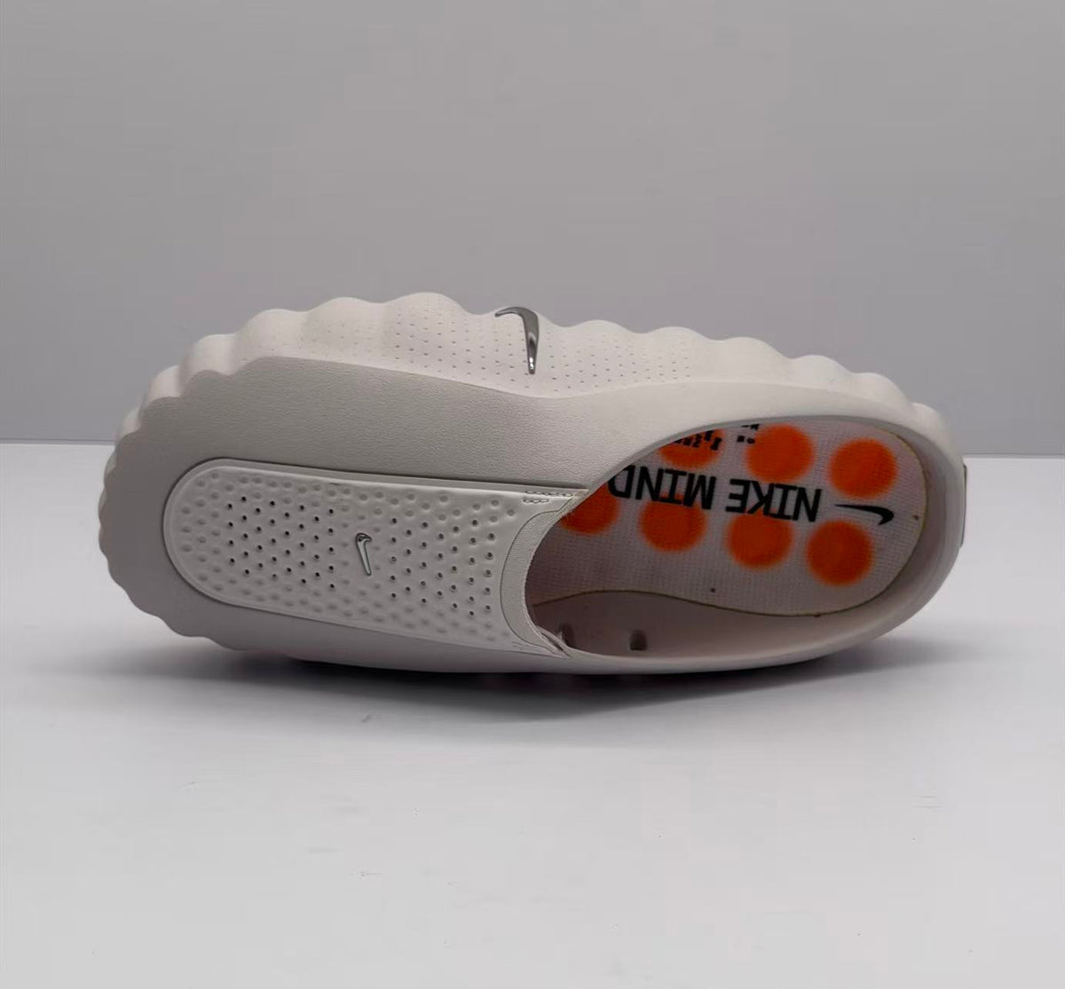 Top and side view of one slide sandal showing the perforated strap, pink footbed, and Nike markings.