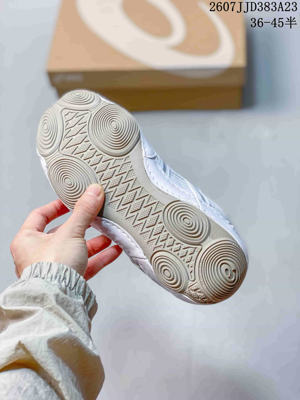 Underside view of the white sneaker showing a flat rubber outsole with circular tread details.