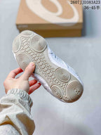 Underside view of the white sneaker showing a flat rubber outsole with circular tread details.