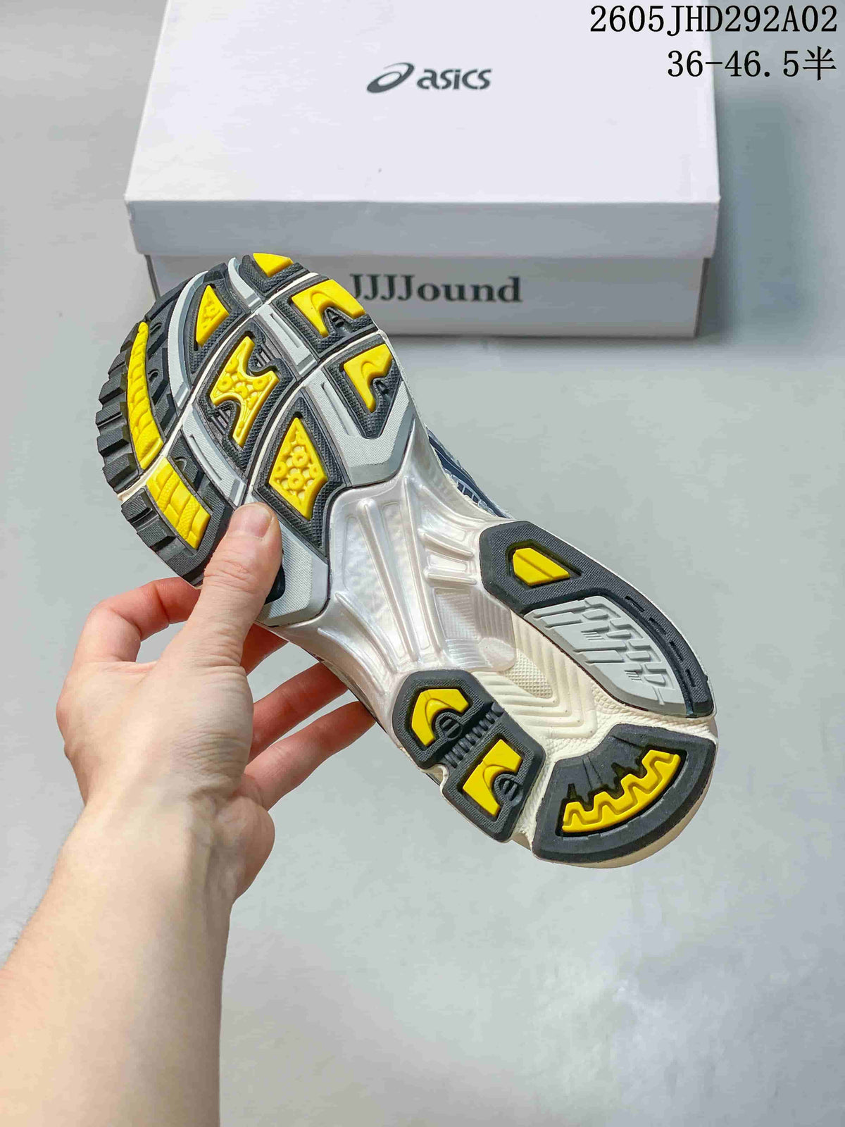 Underside of a sneaker showing a segmented gray, yellow, and black outsole