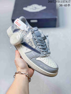 Gray and white low-top sneaker with layered panels, gray laces, and contrasting swoosh-style details.