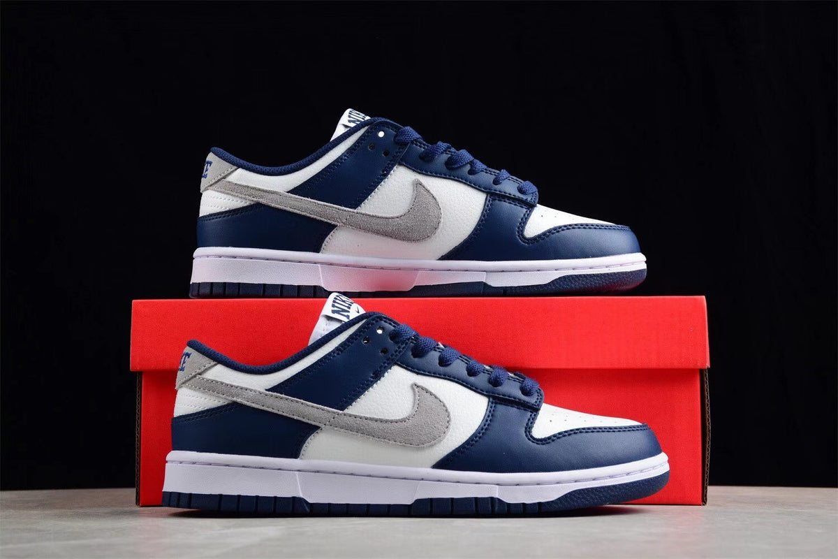 Pair of sneakers displayed against a red shoebox, showing the navy, white, and gray color scheme.