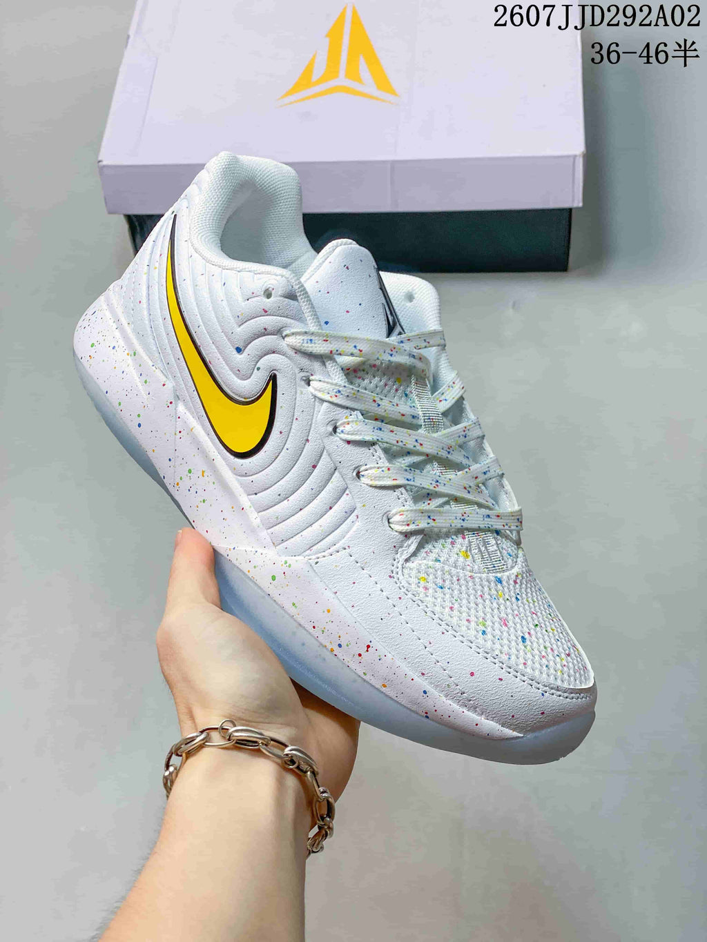 Angled side view of the white basketball shoe showing the yellow and black side logo, speckled upper, and translucent sole.