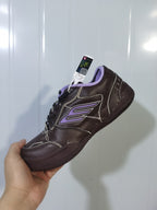 Angled view of the dark brown sneaker showing the light-purple collar trim, side detailing, black laces, and outsole.