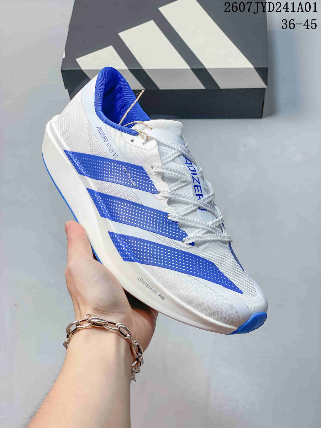 Side view of a white Adidas Adizero running shoe with blue stripes and a blue collar; image displays the size range 36–45.