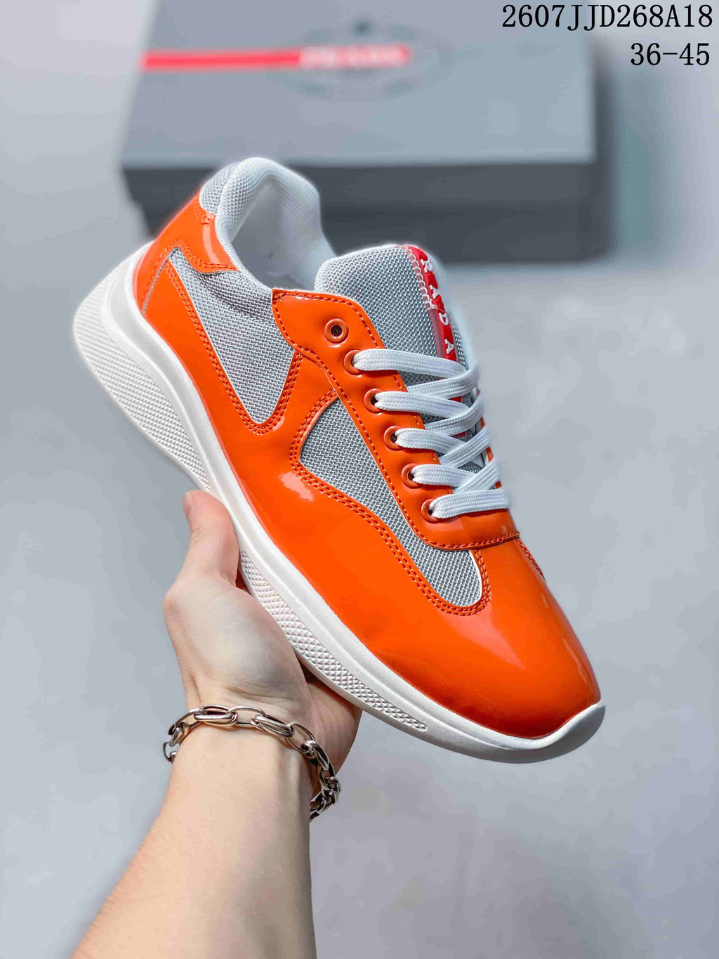 Angled side view of the orange and gray low-top sneaker showing its lace-up construction and white textured sole.