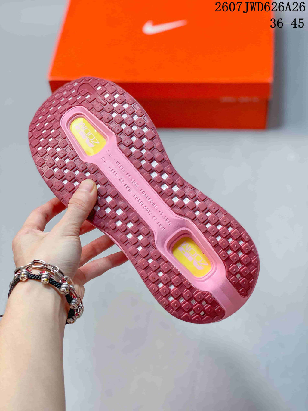 Pink sneaker outsole showing a square-pattern tread and yellow branded inserts, with 2607JWD626A26 and 36–45 visible in the image.