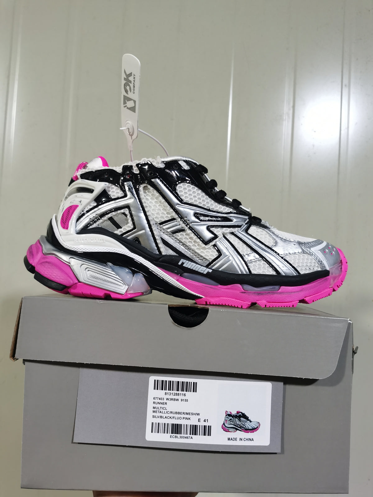 Side-profile sneaker displayed on its box; the label shows model code 9155, silver/black/fluorescent pink color text and size E 41.