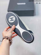 Underside view of a sneaker showing the black-and-white outsole with circular tread sections and a central Chanel emblem.