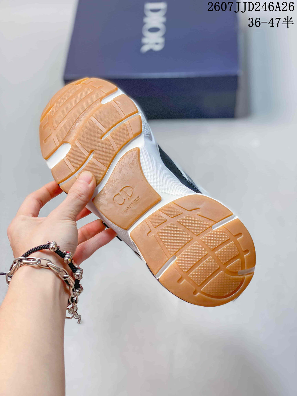 Underside view of a Dior sneaker showing the gum-colored patterned outsole and Dior-marked midfoot section.