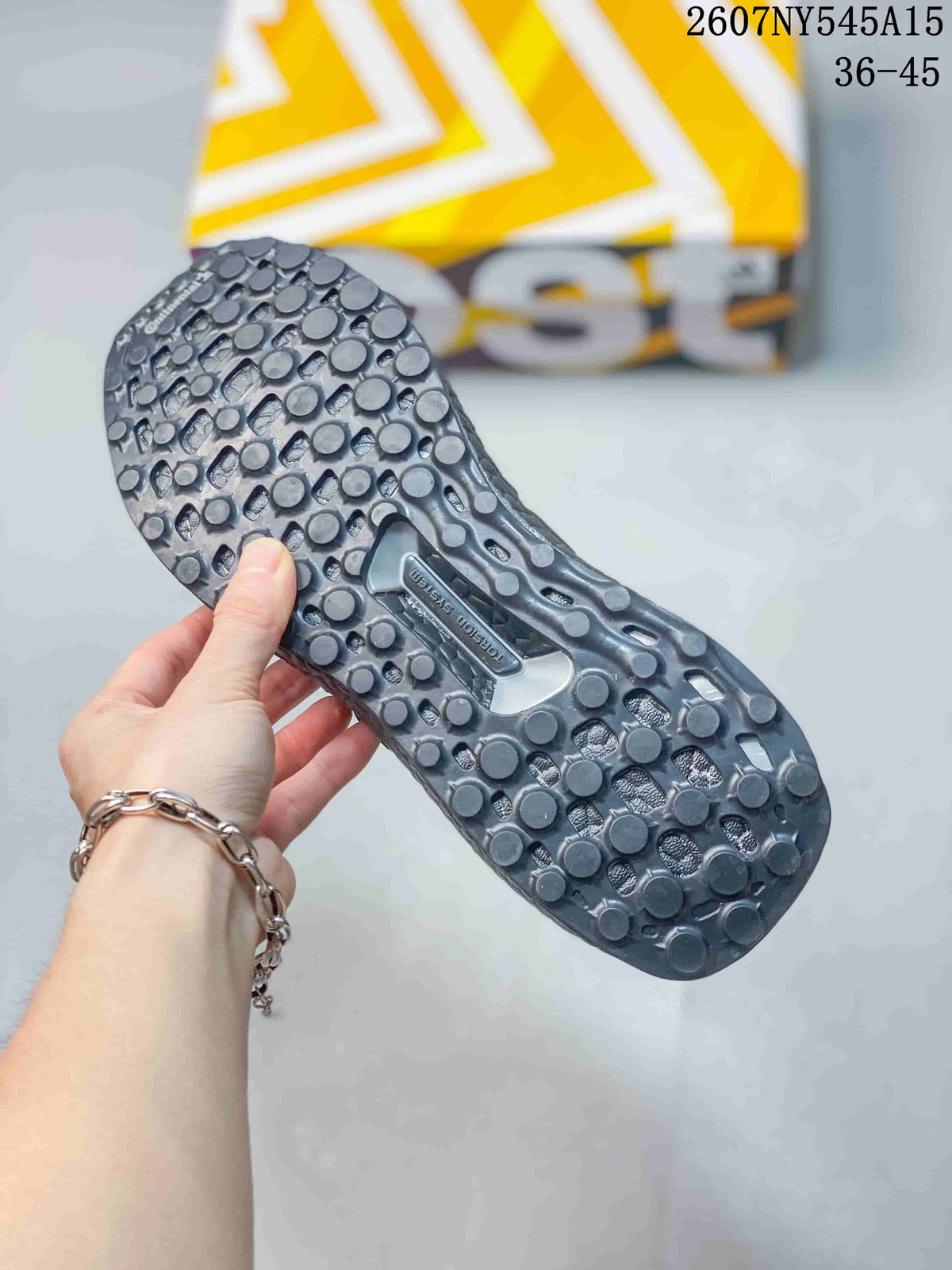 Close-up of the patterned outsole on a dark gray sneaker, showing rounded traction elements and the molded midfoot section.
