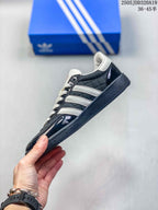 Side profile showing the black upper, white three-stripe detailing, glossy overlays and low-top silhouette.