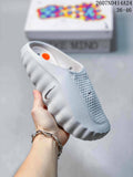 Light gray Nike Mind 001 slip-on slide with perforated panels and a textured outsole, shown in hand.