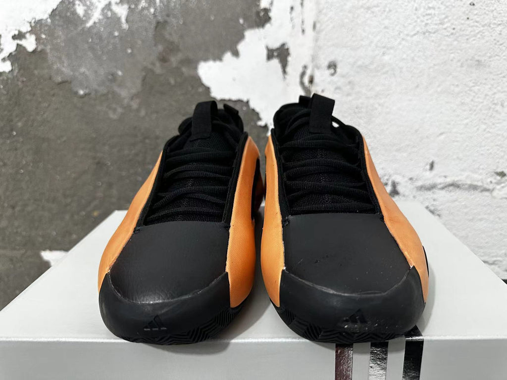 Front view of black and orange lace-up basketball shoes.