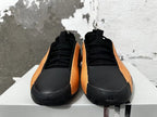 Front view of black and orange lace-up basketball shoes.