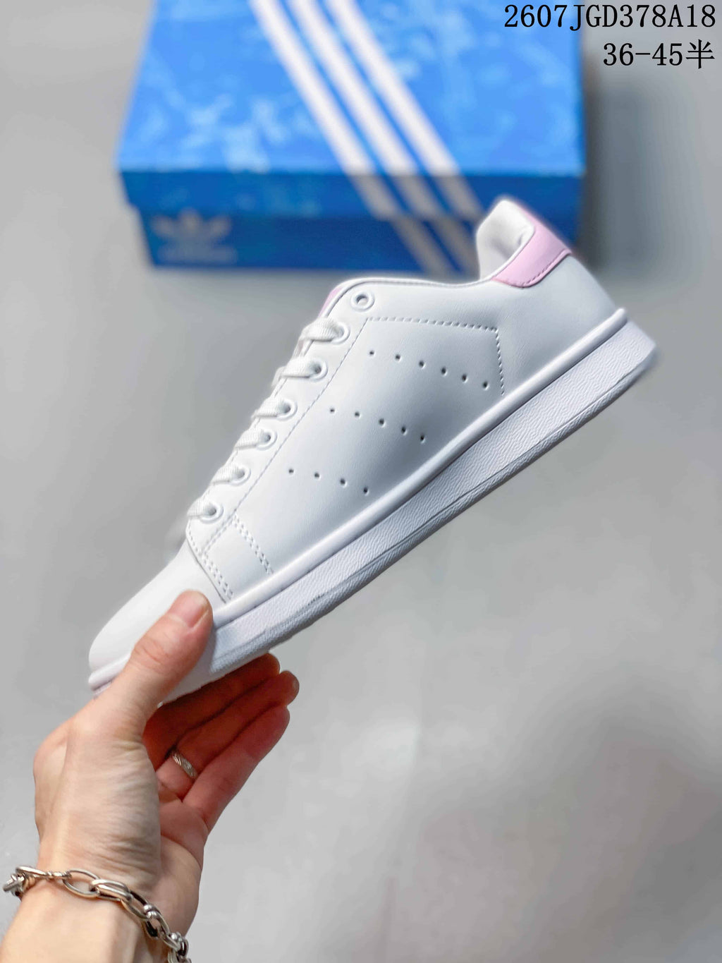 Side view showing the white upper, perforated panel, pink heel accent, laces, and flat rubber sole.