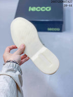 Close view of the light-colored outsole with a repeating raised pattern, with ECCO packaging in the background.
