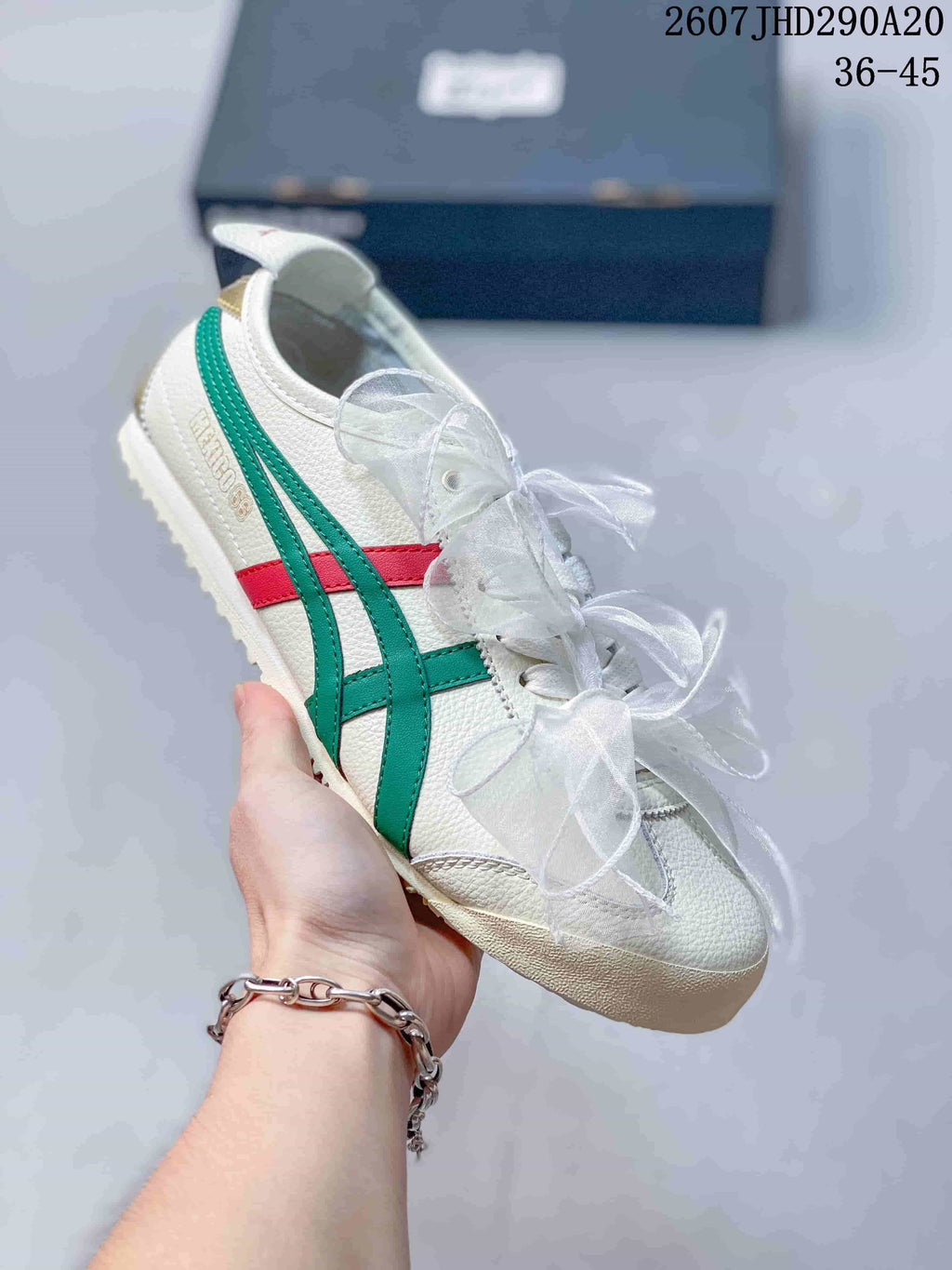 Close angled view of a white sneaker with green and red stripes and textured upper panels.