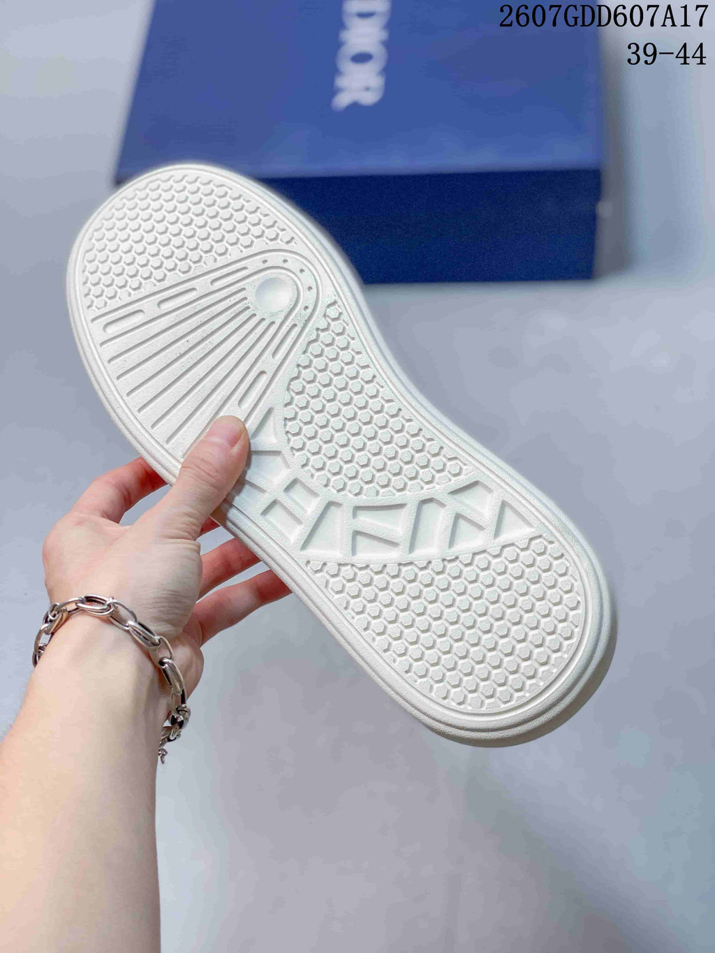 Underside of a white sneaker showing the patterned rubber outsole tread.