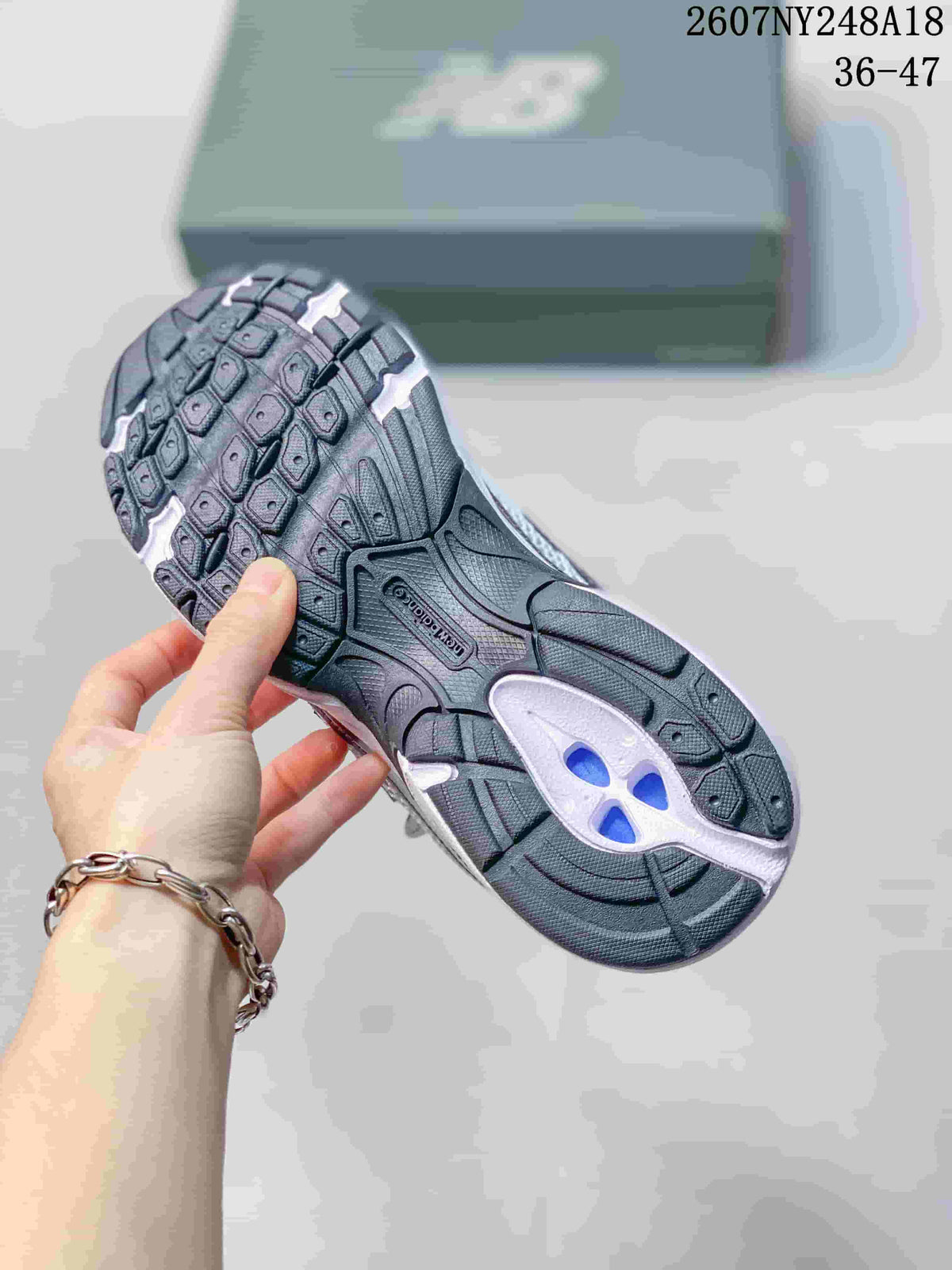 Underside of a New Balance sneaker showing the black and white patterned outsole and central tread detail.