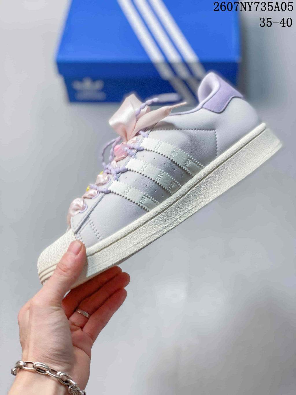 Side view showing the white upper, three side stripes, lilac collar, and layered rubber sole.
