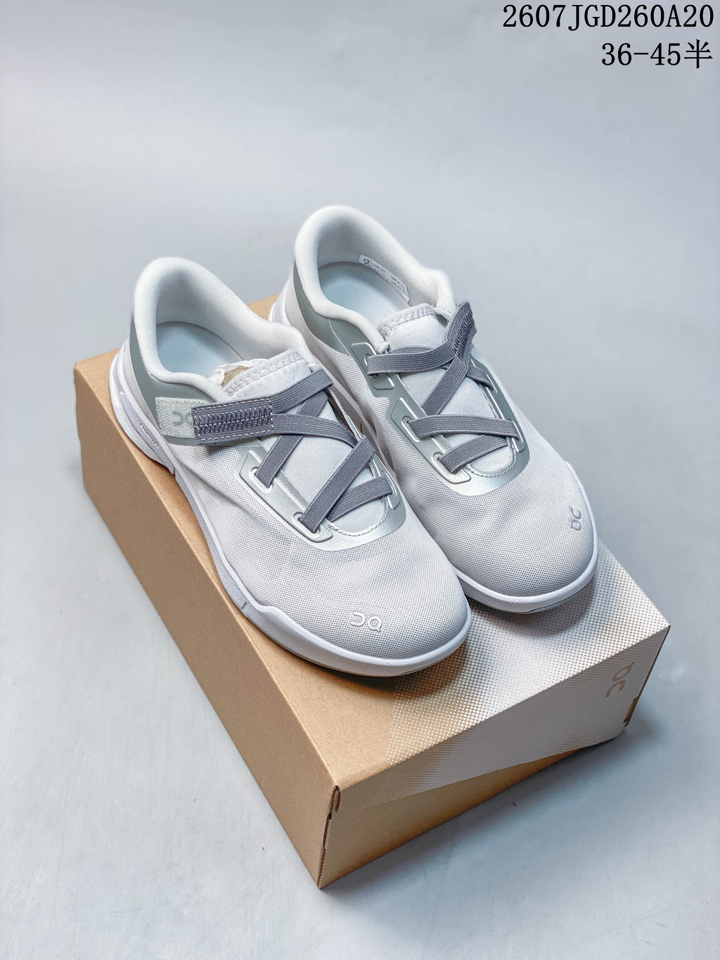 Pair of light gray and white On sneakers displayed on a shoe box, with gray strap detailing and the product size range printed above.