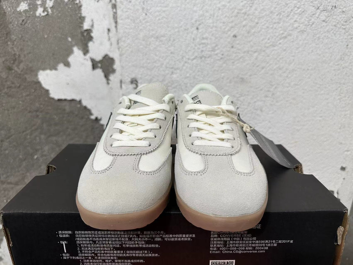 Front view showing the cream low-top sneakers, white laces, and gum-colored outsoles