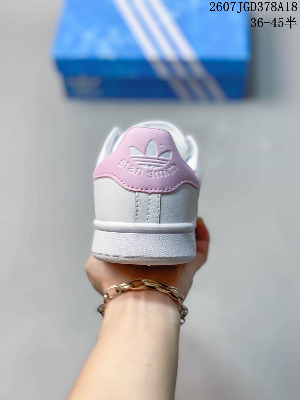 Rear view showing the pink heel panel, white upper, and Stan Smith branding.