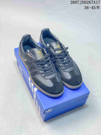 Black adidas Samba sneakers displayed on a blue shoebox, with gold-tone branding and a visible size range marking.