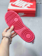Red outsole of a Nike sneaker showing circular traction patterns and embossed branding.