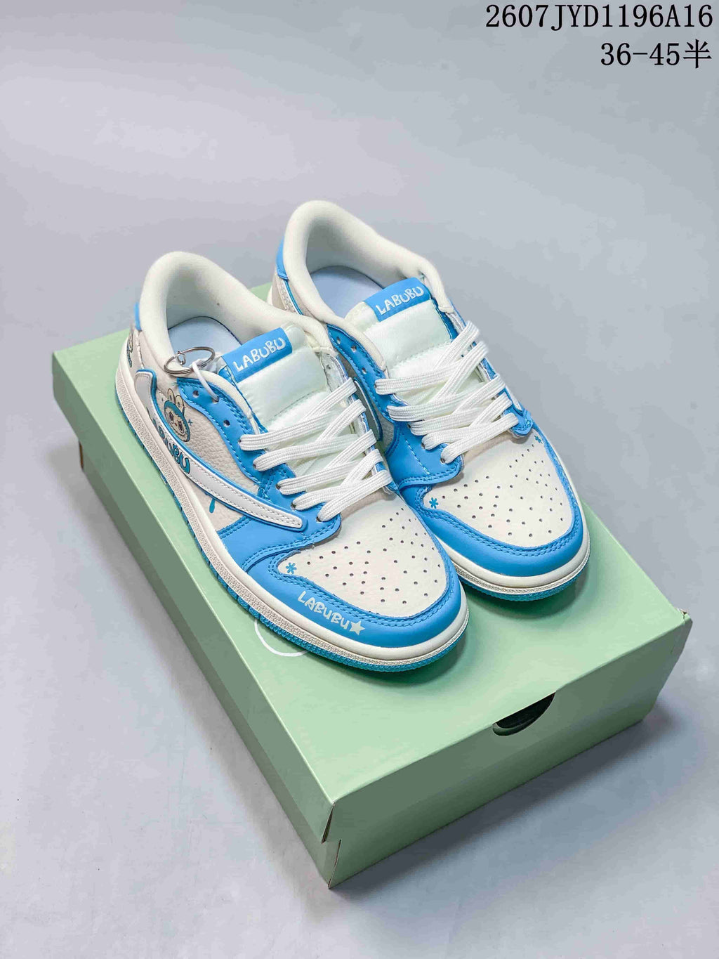 Pair of blue and white low-top Jordan sneakers displayed on a green shoe box, with Labubu text on the tongues and toe edges.