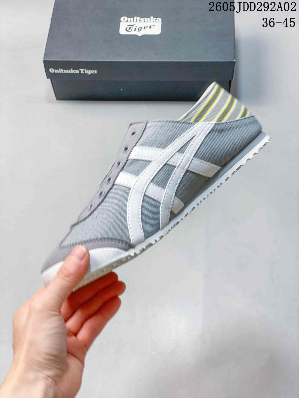 Side view showing the gray upper, white side stripes, slip-on opening, and white outsole.