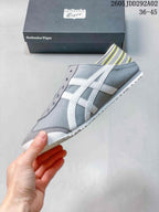 Side view showing the gray upper, white side stripes, slip-on opening, and white outsole.